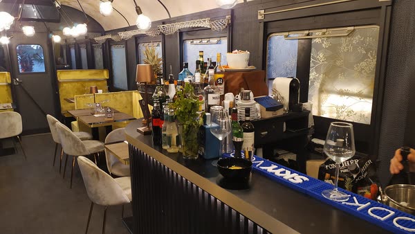 Il bancone bar dentro la carrozza, con le bottiglie in fila e i tavoli del vagone sullo sfondo