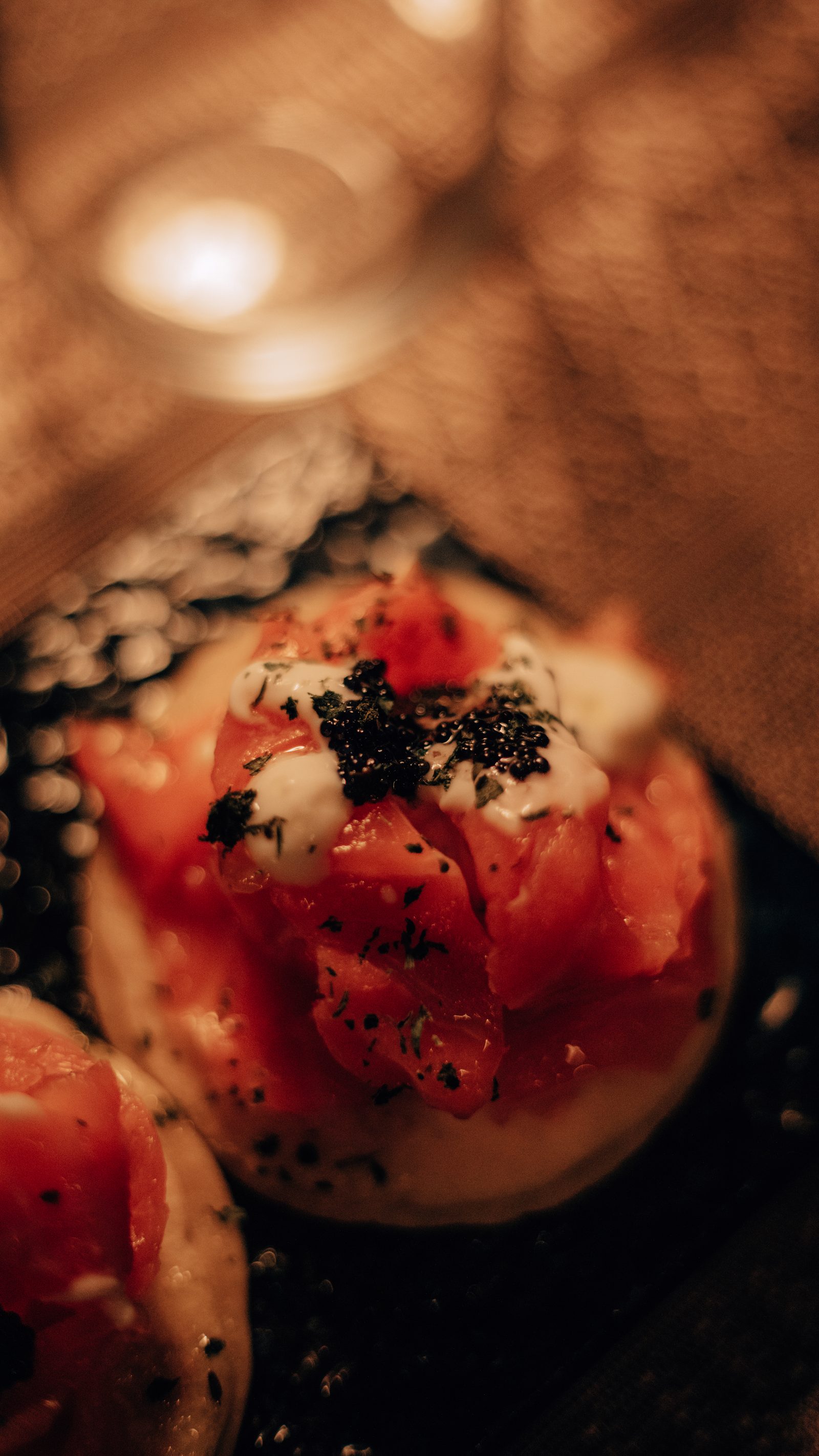 Blinis con salmone marinato, panna acida e caviale, fotografati da vicino sotto la luce calda del vagone