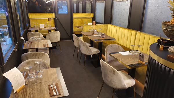 La sala della carrozza apparecchiata: divanetti di velluto oro, sedie grigie e tavoli con i calici